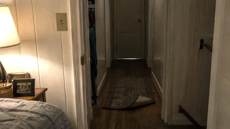 Unlit hallway with a loose throw rug, a common fall hazard in older New Jersey homes